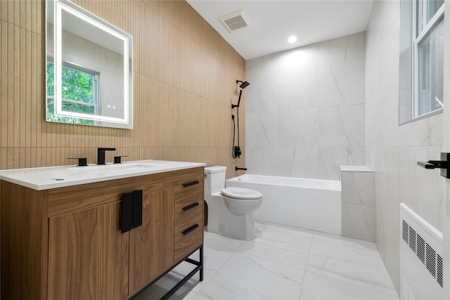 full bathroom with vanity, toilet, tile walls, and tiled shower / bath combo