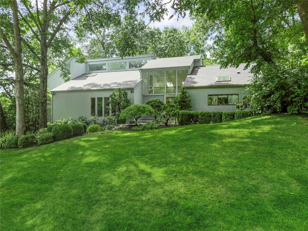 back of house featuring a lawn and a sunroom