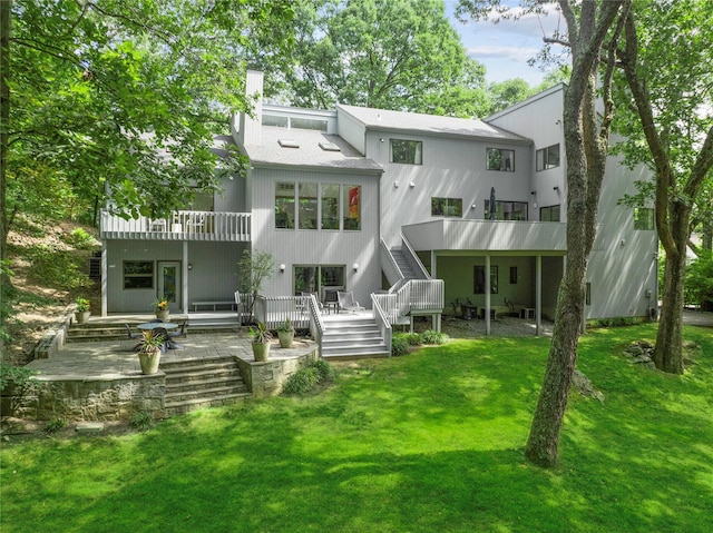 back of property with a balcony and a lawn