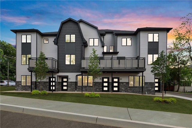 view of front of house featuring a yard and a balcony