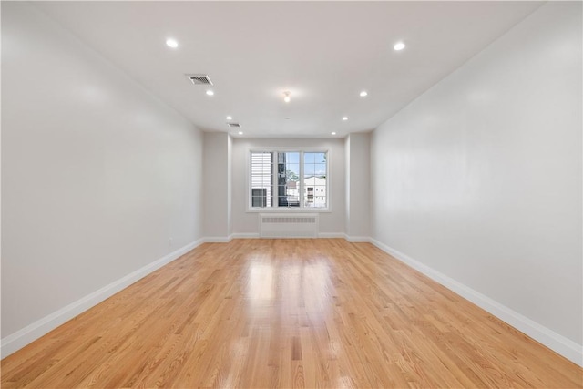 spare room featuring light wood-type flooring and radiator