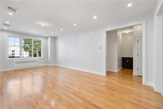 unfurnished room featuring light wood-type flooring and radiator heating unit