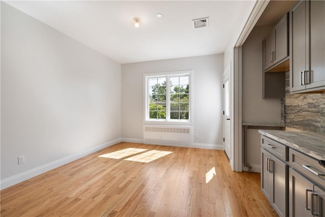 unfurnished dining area featuring light wood-type flooring and radiator heating unit