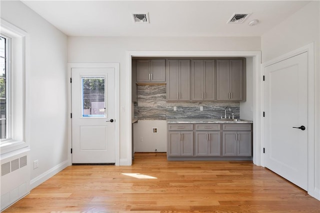 kitchen featuring light hardwood / wood-style floors, sink, radiator, and tasteful backsplash