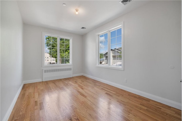 empty room with light hardwood / wood-style floors and radiator heating unit