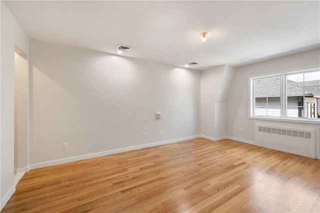 empty room with radiator and light hardwood / wood-style flooring