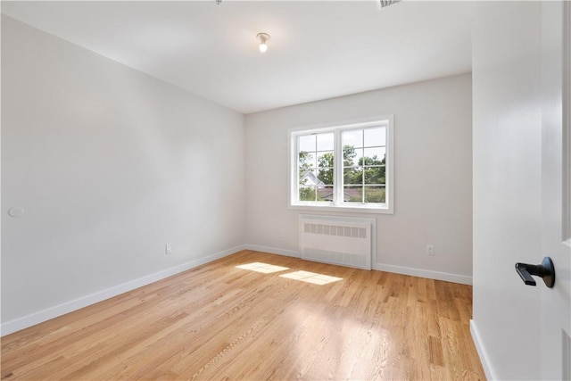 unfurnished room featuring light wood-type flooring and radiator