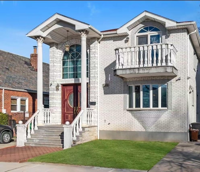 view of front of home featuring a balcony and a front lawn