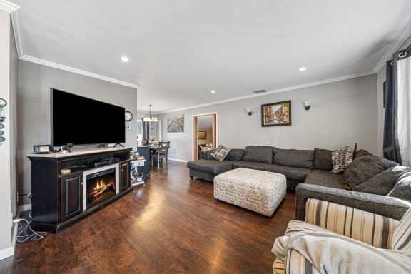 living room with crown molding, dark hardwood / wood-style flooring, and a notable chandelier