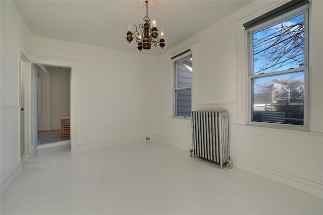 unfurnished room with radiator heating unit and a chandelier