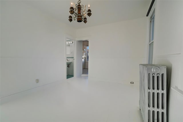 unfurnished room featuring radiator heating unit and an inviting chandelier