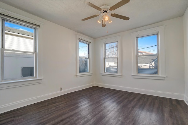 spare room with a textured ceiling, a wealth of natural light, dark hardwood / wood-style flooring, and ceiling fan