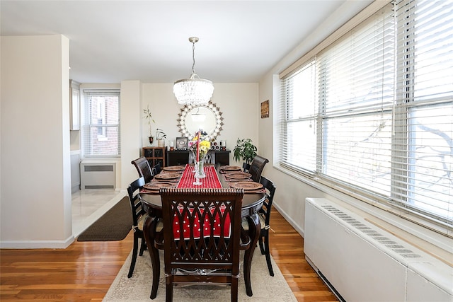 dining space featuring radiator, hardwood / wood-style floors, and a chandelier