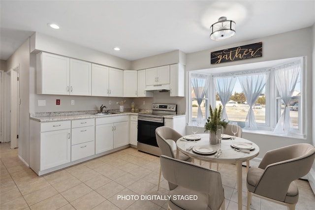 kitchen featuring stainless steel electric stove, sink, light stone countertops, light tile patterned flooring, and white cabinetry