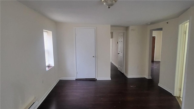 unfurnished room with dark hardwood / wood-style flooring and baseboard heating