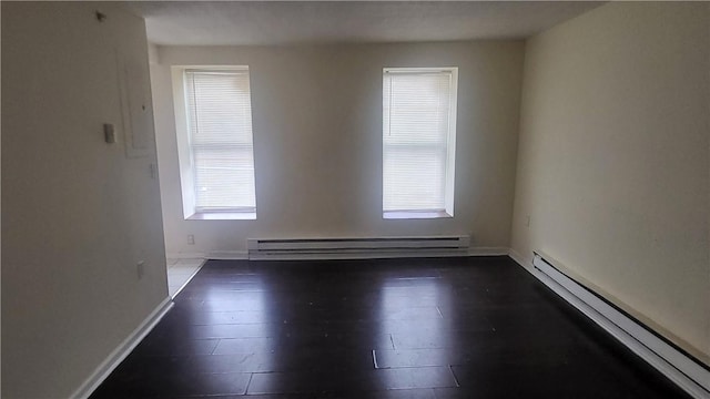 unfurnished room featuring dark hardwood / wood-style flooring and a baseboard heating unit