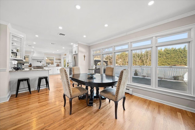 dining space with light hardwood / wood-style floors and crown molding