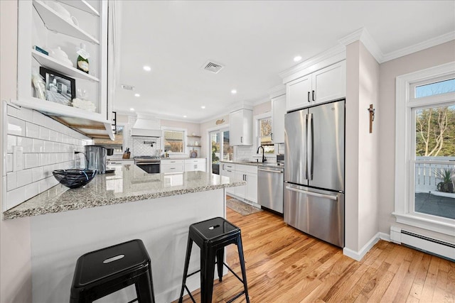 kitchen featuring sink, stainless steel appliances, kitchen peninsula, decorative backsplash, and white cabinets