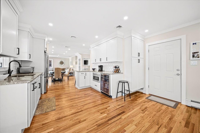 kitchen featuring white cabinets, stainless steel fridge, backsplash, and sink