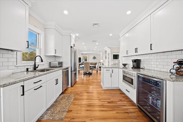 kitchen with sink, wine cooler, light hardwood / wood-style floors, white cabinets, and appliances with stainless steel finishes