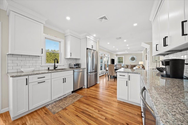 kitchen with stainless steel appliances, white cabinetry, crown molding, and sink