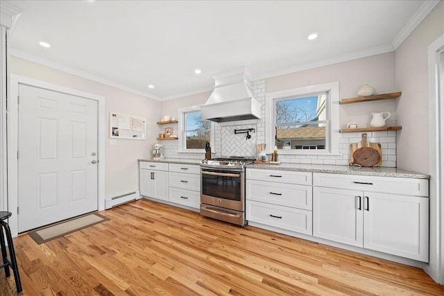 kitchen with premium range hood, white cabinets, stainless steel range, tasteful backsplash, and a baseboard radiator