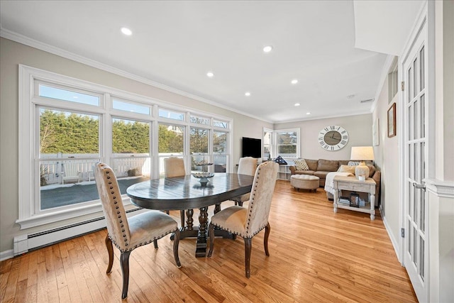 dining room featuring light hardwood / wood-style floors, ornamental molding, and a baseboard heating unit