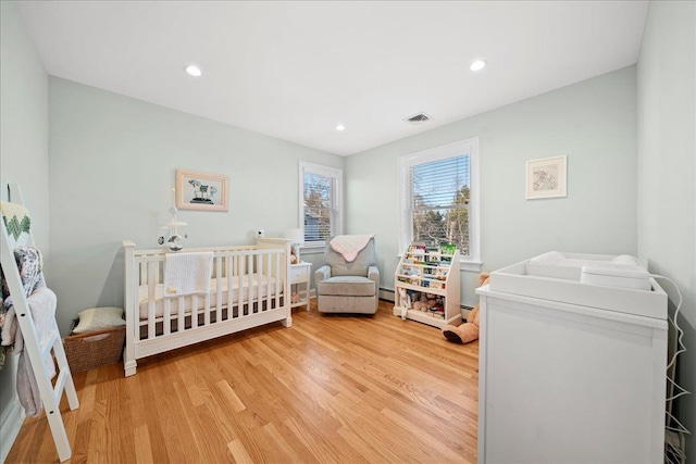 bedroom featuring a crib and hardwood / wood-style flooring