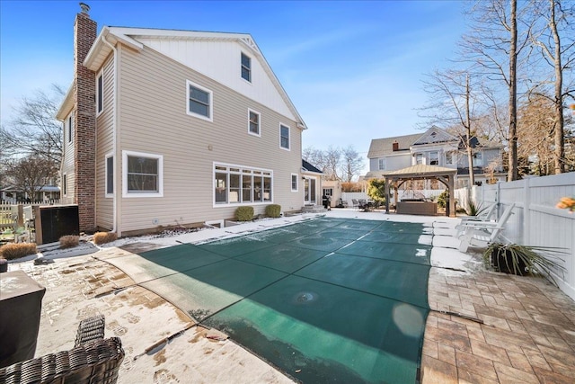 back of property with a gazebo, a patio area, and a covered pool