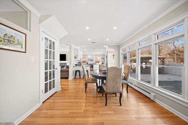 dining area with light hardwood / wood-style floors, crown molding, and a baseboard heating unit