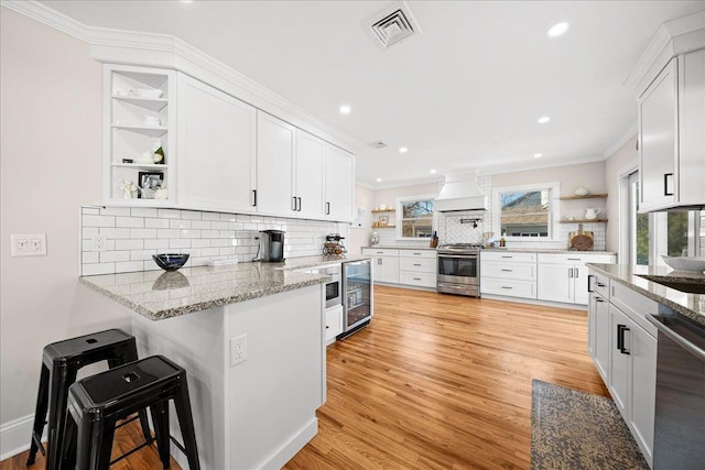 kitchen featuring white cabinetry, stainless steel appliances, a breakfast bar area, decorative backsplash, and custom exhaust hood