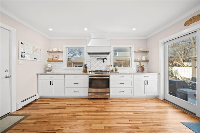 kitchen with stainless steel range, premium range hood, white cabinetry, and a baseboard heating unit