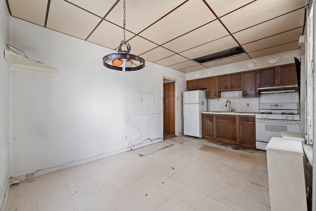 kitchen with tasteful backsplash, sink, white appliances, hanging light fixtures, and a paneled ceiling