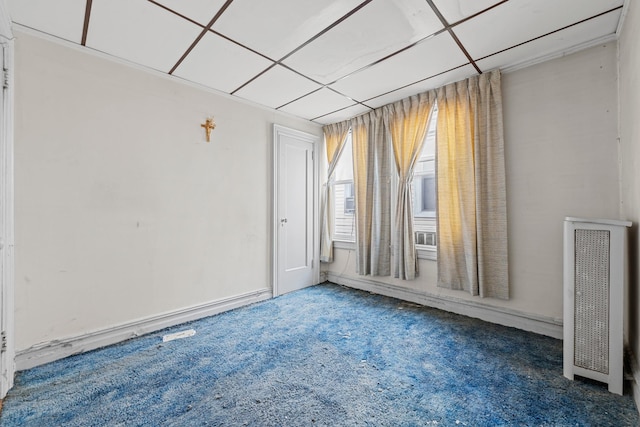 carpeted empty room with radiator and a paneled ceiling