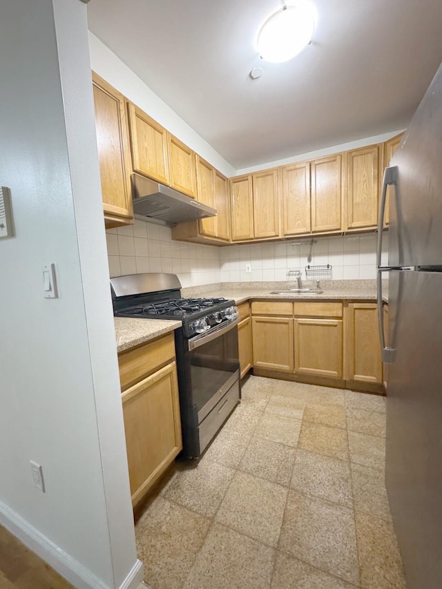 kitchen with gas stove, stainless steel fridge, backsplash, and sink