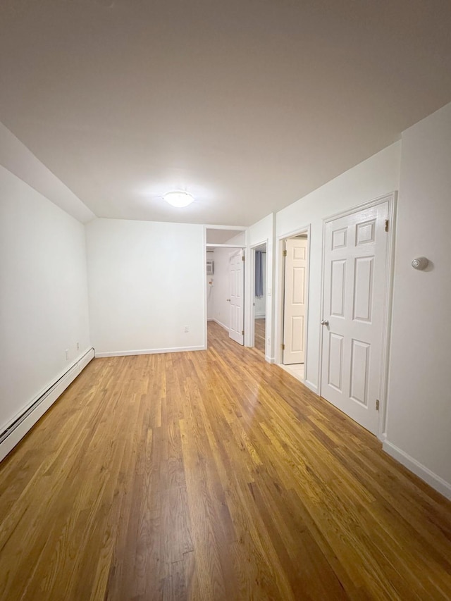 interior space featuring a baseboard heating unit and light hardwood / wood-style floors