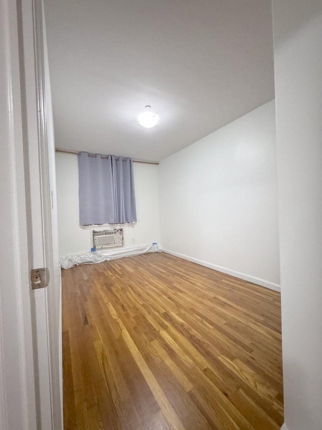 spare room featuring a wall unit AC and hardwood / wood-style flooring