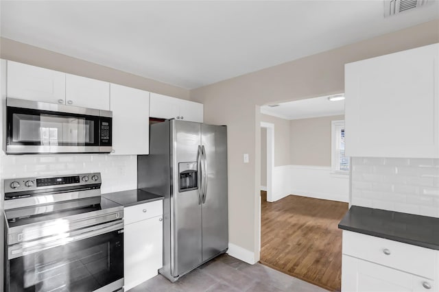 kitchen with white cabinets, stainless steel appliances, tasteful backsplash, and light tile patterned flooring