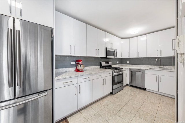 kitchen with white cabinets, appliances with stainless steel finishes, decorative backsplash, and sink