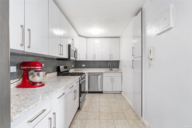 kitchen featuring white cabinetry, sink, light stone countertops, tasteful backsplash, and appliances with stainless steel finishes