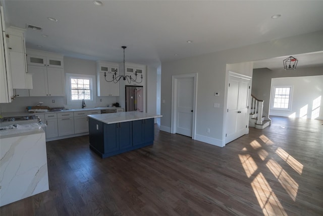 kitchen with high quality fridge, white cabinets, hanging light fixtures, and a kitchen island