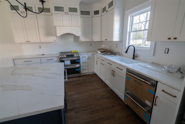 kitchen featuring light stone counters, stainless steel range, dark wood-type flooring, sink, and white cabinets