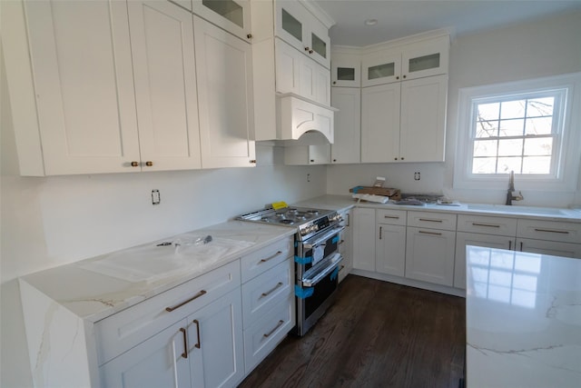 kitchen featuring white cabinets, dark hardwood / wood-style floors, range with two ovens, and light stone countertops