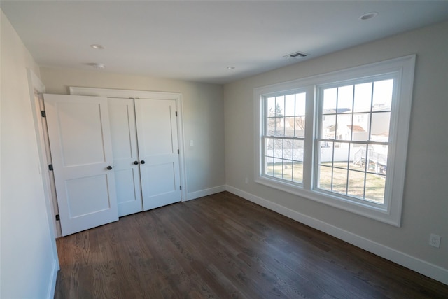 unfurnished bedroom featuring dark hardwood / wood-style flooring and a closet