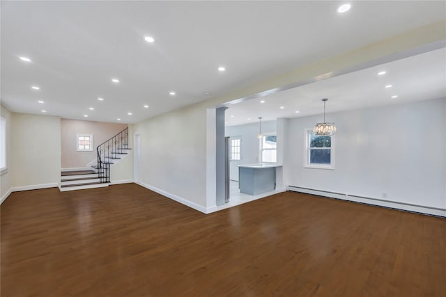 unfurnished living room with dark wood-type flooring, a baseboard radiator, and a notable chandelier