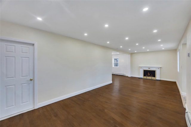 unfurnished living room featuring dark wood-type flooring and a baseboard radiator