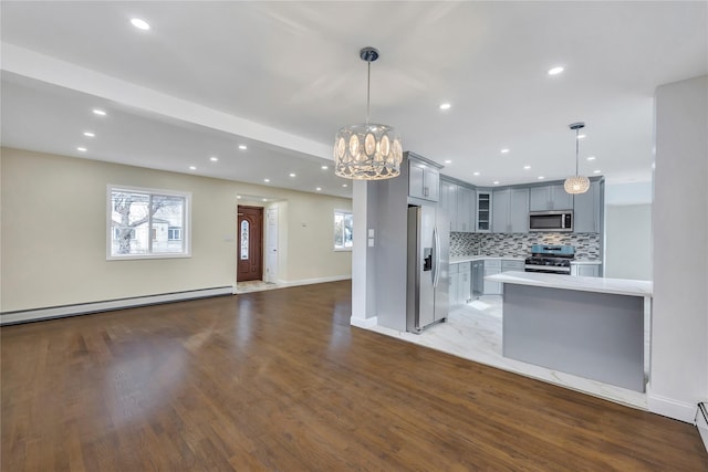 kitchen featuring hanging light fixtures, stainless steel appliances, an inviting chandelier, a baseboard heating unit, and gray cabinets