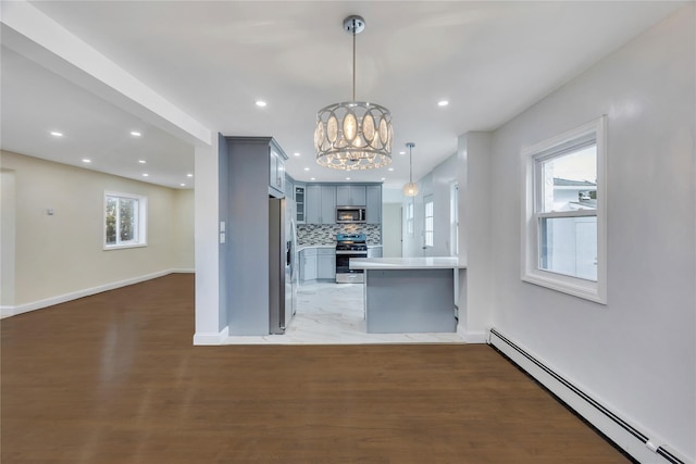 kitchen featuring hanging light fixtures, stainless steel appliances, an inviting chandelier, a baseboard heating unit, and backsplash