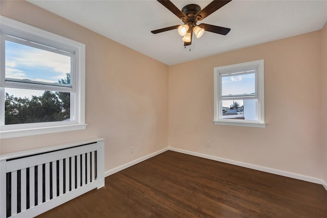 spare room with radiator heating unit, dark hardwood / wood-style flooring, and ceiling fan