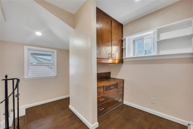 corridor with plenty of natural light, baseboard heating, and dark wood-type flooring